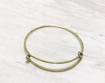May include: A gold-toned expandable bangle bracelet with a simple design.