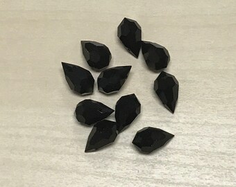 May include: A group of ten black teardrop-shaped crystal beads.