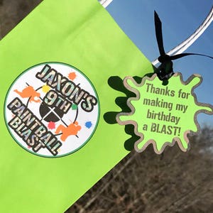 May include: A green favor bag with a white handle and a round sticker that says "Jaxon's 9th Paintball Blast". A green and brown splatter paint sticker with the text "Thanks for making my birthday a BLAST!" is attached to the bag.