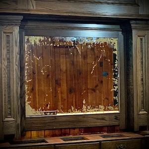 May include: A dark wood cabinet with a large rectangular mirror with a distressed glass surface. The cabinet has three drawers with ornate metal pulls.