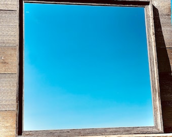 May include: A rustic wooden frame with a mirror reflecting a clear blue sky.