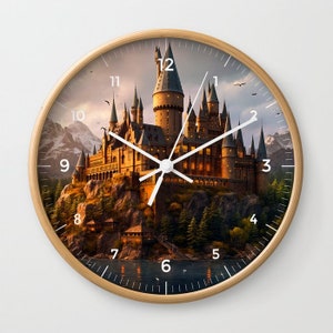 May include: Round wall clock with a light wood frame. The clock face features a detailed illustration of a castle on a hill, with a lake and mountains in the background. The clock hands are white.