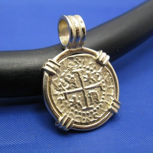 May include: Gold-toned pendant featuring a round coin with a cross design. The coin is surrounded by a decorative border.