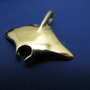 May include: A silver-coloured manta ray charm pendant. The pendant is shaped like a manta ray with a loop at the top for attaching to a chain or bracelet.