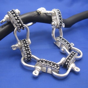 May include: A silver bracelet with a chain link design. Each link is decorated with a row of small beads.