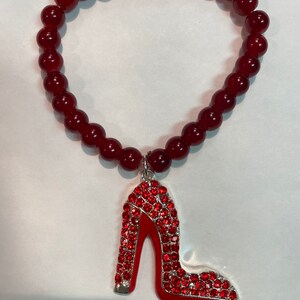 May include: A red beaded bracelet with a red rhinestone high heel shoe charm.