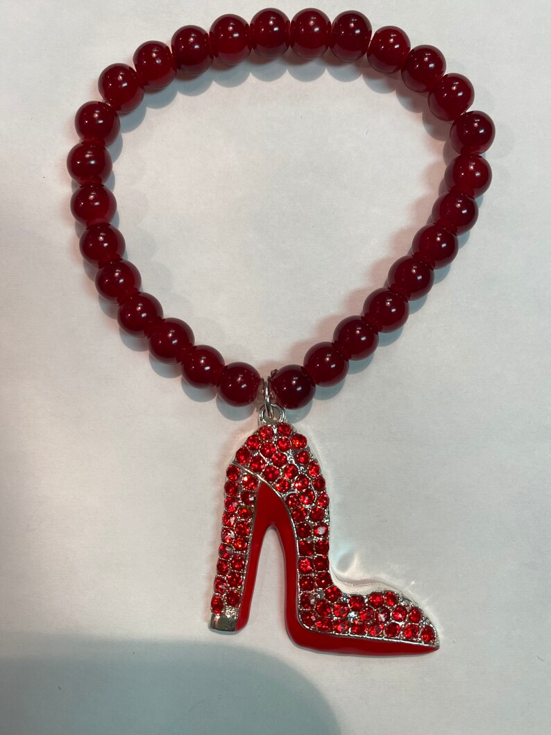 May include: A red beaded bracelet with a red rhinestone high heel shoe charm.