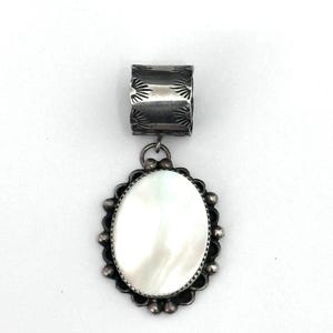 May include: A silver pendant with a white mother-of-pearl oval stone set in a silver bezel. The pendant has a silver bail with a decorative design.