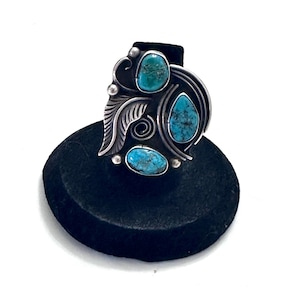 May include: A silver ring featuring three turquoise stones set in a leaf design.