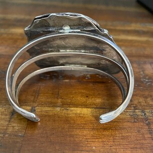 May include: Silver cuff bracelet with a textured, irregular shaped design. The bracelet is open and has a hinged closure.
