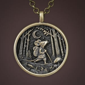 May include: A bronze pendant necklace featuring a detailed, three-dimensional design of a mouse carrying a backpack and walking through a forest under a crescent moon.