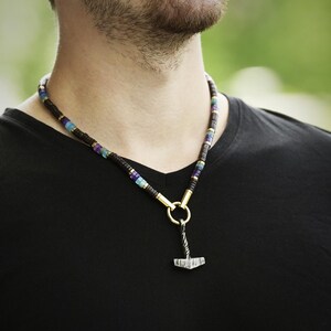 May include: A beaded necklace with a silver hammer pendant. The beads are black, blue, and purple.