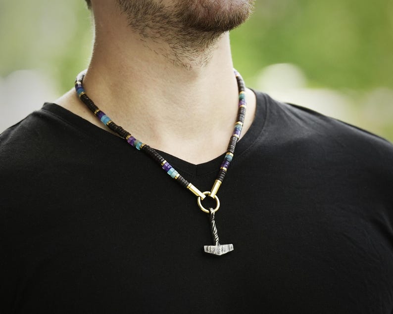 May include: A beaded necklace with a silver hammer pendant. The beads are black, blue, and purple.