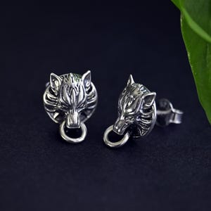 Puede incluir: Un par de pendientes de plata con un dise&ntilde;o de cabeza de lobo. La cabeza de lobo est&aacute; detallada con dientes afilados y una expresi&oacute;n feroz. Los pendientes son un accesorio &uacute;nico y elegante.