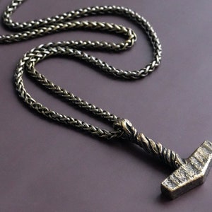 May include: A silver chain necklace with a detailed silver hammer pendant. The chain is a braided style.