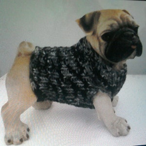 May include: A ceramic pug dog figurine wearing a black and gray knitted sweater. The pug has a tan and black face with a black nose and dark eyes. The sweater covers the dog's body, leaving its legs and tail exposed.