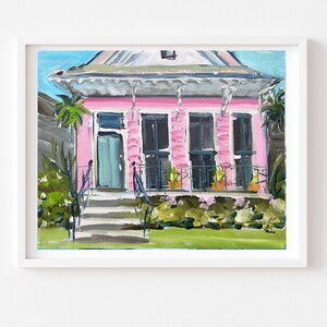 Puede incluir: Una pintura de una casa rosa con una puerta turquesa y molduras blancas. La casa tiene un porche con barandillas negras y plantas en macetas. La casa est&aacute; rodeada de hierba verde y arbustos.