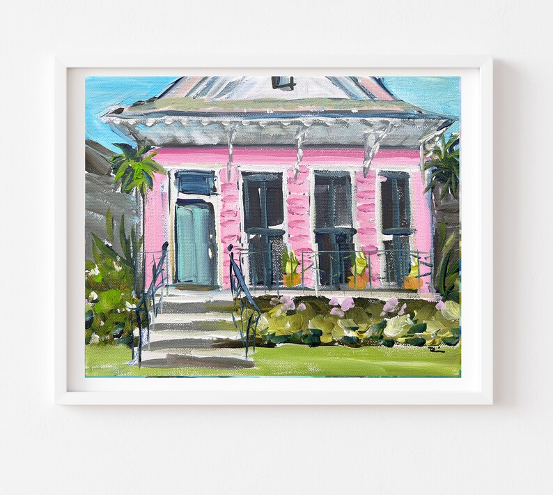 Puede incluir: Una pintura de una casa rosa con una puerta turquesa y molduras blancas. La casa tiene un porche con barandillas negras y plantas en macetas. La casa est&aacute; rodeada de hierba verde y arbustos.