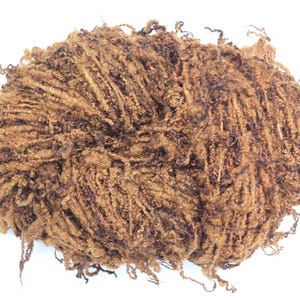 May include: A ball of textured brown yarn with a fuzzy, irregular appearance. The yarn consists of multiple strands wound together, creating a dense, tangled structure with loose fibers extending from the surface in various directions.