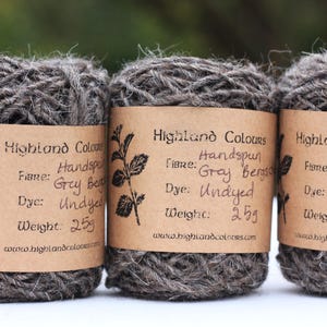 Puede incluir: Tres ovillos de hilo de lana Bergschaf gris hilado a mano, cada uno etiquetado con "Highland Colours" con la fibra, el tinte y el peso. El hilo no está teñido y pesa 25 g cada uno.