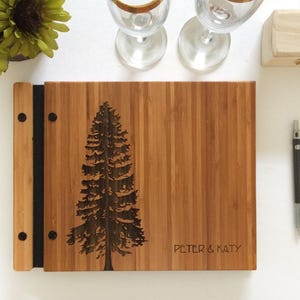 Custom wooden guest log, featuring a large pine tree and custom names engraved in the cover.