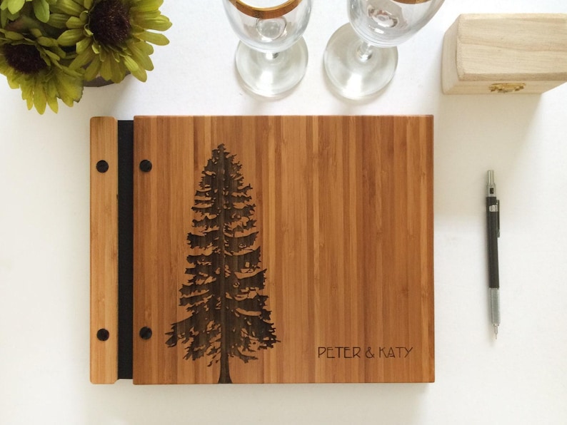Custom wooden guest log, featuring a large pine tree and custom names engraved in the cover.
