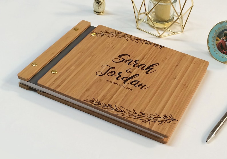 Engraved wooden guest book in an amber finish with customized couples names and boho leaf design engraving.