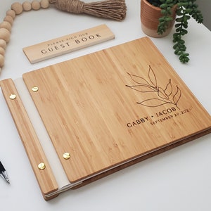 Minimalist bamboo wedding guest book in an amber finish with engraved, customized couples names and a boho leaf design on the cover.