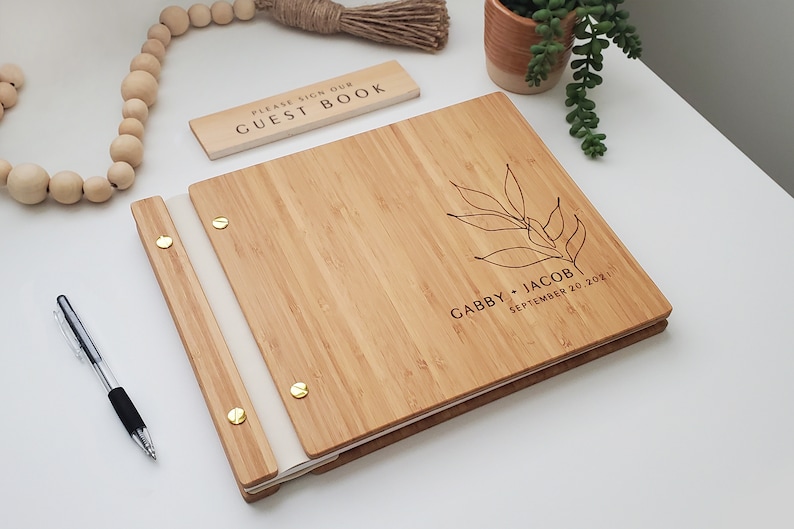 Custom bamboo wedding guest book in an amber finish, personalized with the couples names and event date and a boho leaf design on the cover.