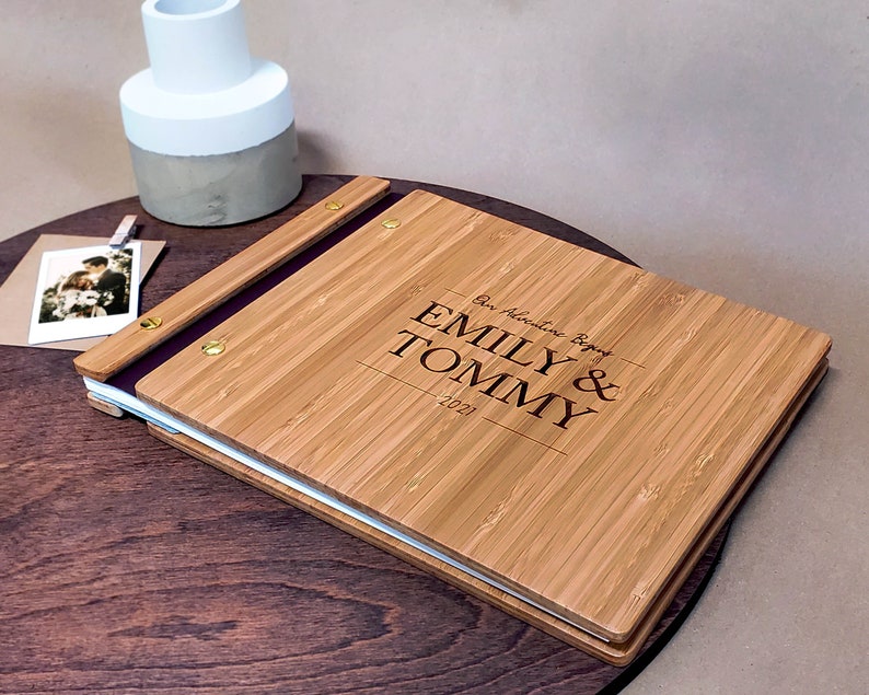 Customized wedding guest book featuring a minimalist engraved design sits on a small table.