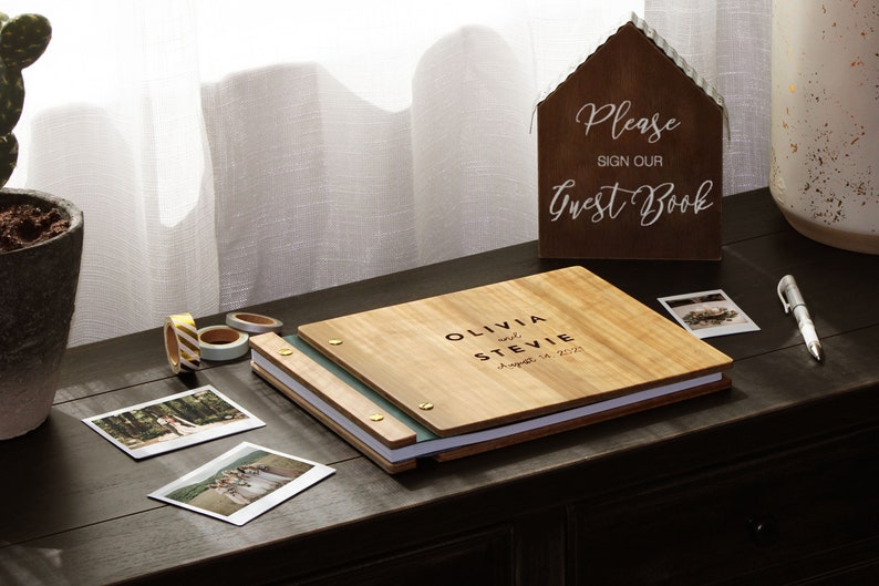 Custom instant photo booth album rests on a table, next to images taken during the event, ready to be attached to the interior pages and for the guests to sign.