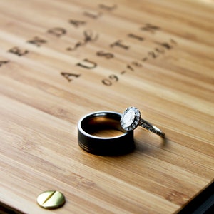 Close-up of a couples wedding rings resting on the cover of their custom wooden guest book.