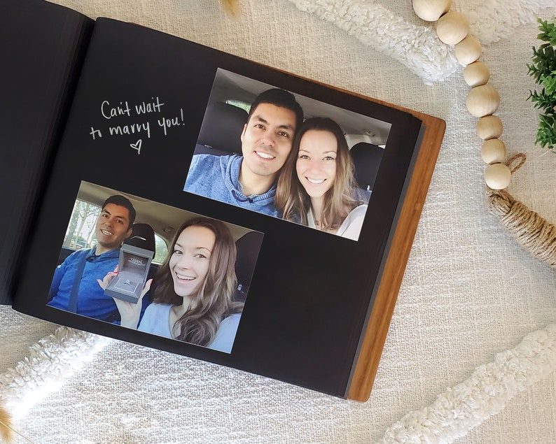 Close-up of interior of 5th anniversary wedding album, featuring photos attached to archival black paper and messages written alongside.