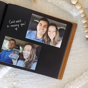 Close-up of interior of first anniversary wedding album, featuring photos attached to archival black paper and messages written alongside.