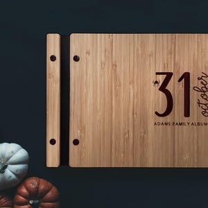 A Halloween family photo album sits on a table beside some festive pumpkins.