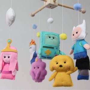 以下が含まれることがあります： アドベンチャータイムのキャラクターがフェルトで作られたベビーモバイルです。フィン、ジェイク、バブルガム姫、マーセリン、ビーエムオー、炎の姫などがあります。モバイルは木でできており、白い雲がぶら下がっています。