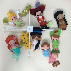 Pu&ograve; includere: Un mobile bianco con personaggi di feltro appesi. I personaggi includono Trilly, Peter Pan, Capitan Uncino, una sirena, una donna nativa americana, un personaggio di Alice nel Paese delle Meraviglie, un bambino con un orsacchiotto e due stelle gialle.