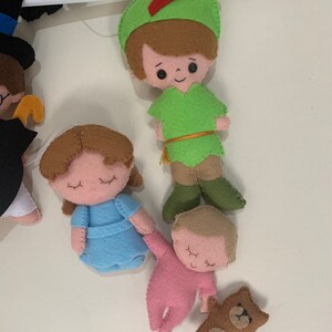 Pu&ograve; includere: Un mobile in feltro con personaggi di Peter Pan, tra cui Peter Pan, Wendy, un bambino e un orsacchiotto. I personaggi sono tutti cuciti a mano e hanno dettagli ricamati.