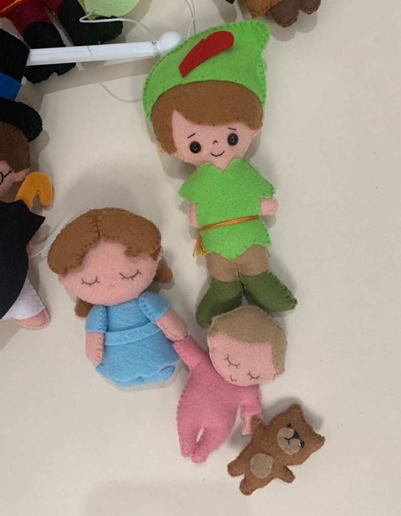 Pu&ograve; includere: Un mobile in feltro con personaggi di Peter Pan, tra cui Peter Pan, Wendy, un bambino e un orsacchiotto. I personaggi sono tutti cuciti a mano e hanno dettagli ricamati.