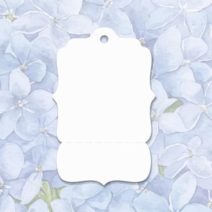 May include: A white, die-cut gift tag with a decorative shape and a hole at the top for stringing. The tag is set against a soft, watercolor background of light blue hydrangea flowers.