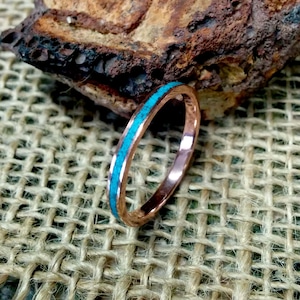 May include: A thin copper band ring with a turquoise inlay.