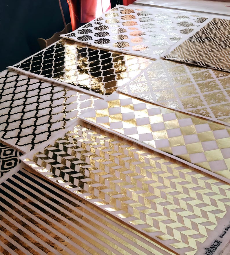 May include: A collection of decorative paper sheets with gold foil patterns. The patterns include geometric shapes, stripes, and floral designs.
