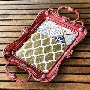 May include: A red serving tray with ornate handles and a decorative gold and blue patterned bottom.