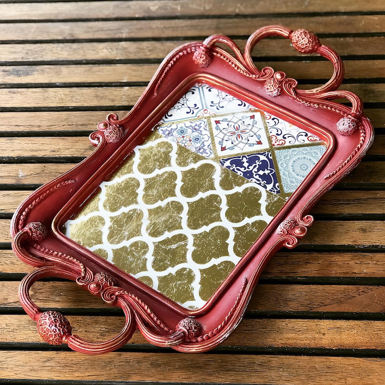 May include: A red serving tray with ornate handles and a decorative gold and blue patterned bottom.
