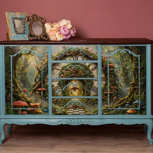 Puede incluir: Un aparador de madera azul claro con una parte superior marrón oscuro y una escena forestal detallada con setas, árboles y un diseño de esfera de reloj en los cajones y puertas. Dos marcos decorativos y un ramo de flores descansan encima.