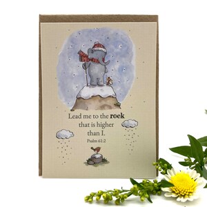 Op de afbeelding: Een aquarel-illustratie van een olifant met een rode hoed en sjaal die op een besneeuwde bergtop staat. De tekst "Leid me naar de rots die hoger is dan ik. Psalm 61:2" staat onder de afbeelding.