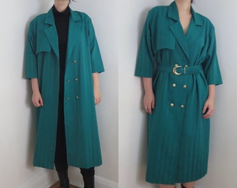 May include: A long, teal green coat with a double breasted closure, a belt, and gold buttons. The coat has a collar and long sleeves.