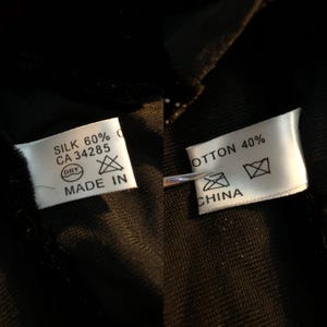 May include: Close-up of two white fabric tags with black text. One tag reads "SILK 60%" and "MADE IN" with a dry clean symbol. The other tag reads "COTTON 40%" and "CHINA" with a dry clean symbol.