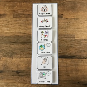 May include: A white visual timetable with six colourful squares. Each square has a different icon and text. The icons represent different activities: carpet time, group work, science, lunch time, RE, and story time.