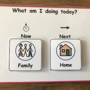 May include: A white visual aid with the text "What am I doing today?"  A clock icon with an arrow pointing down is labelled "Now". A right arrow is labelled "Next". Two square cards with blue borders are below the text. The card on the left has a family icon and the text "Family". The card on the right has a house icon and the text "Home".